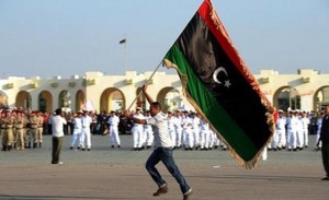 A Libyan man runs with the revolution flag