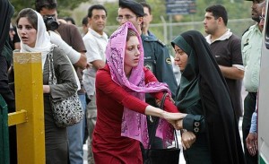A member of the Iranian “morality police” arrests a woman for not wearing her headscarf in the proper manner.