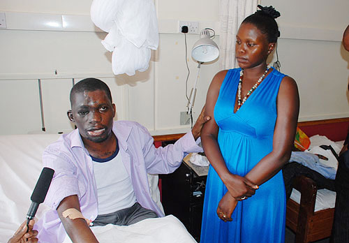Pastor Umar Mulinde on his hospital bed. Standing is his wife. (PHOTONicholas Kajoba)
