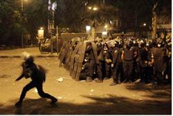 Riot policemen take cover from stones thrown by protesters near U.S. embassy in Cairo - Reuters