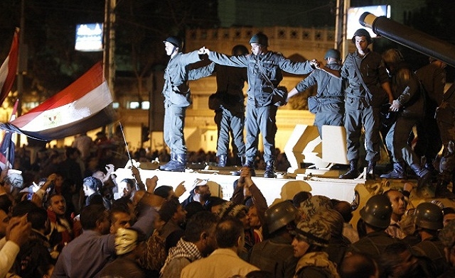 Republican Guard soldiers hold hands standing on a tank - Reuters