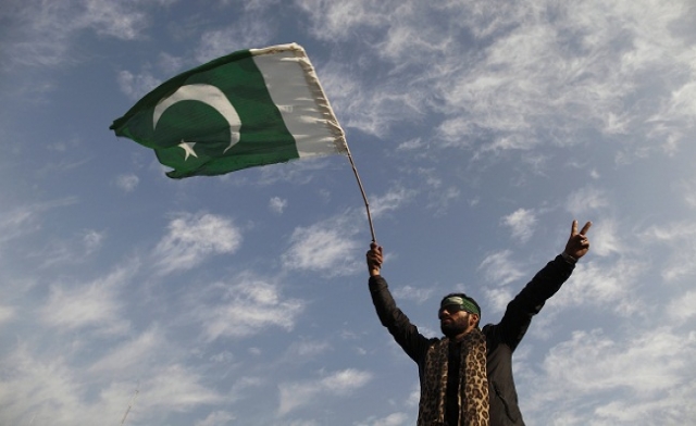 leader of Minhaj-ul-Quran Muhammad Tahirul Qadri waves a Pakistan flag Reuters
