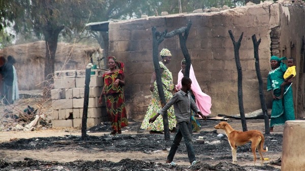 People stand near burnt structures in the aftermath Reuters