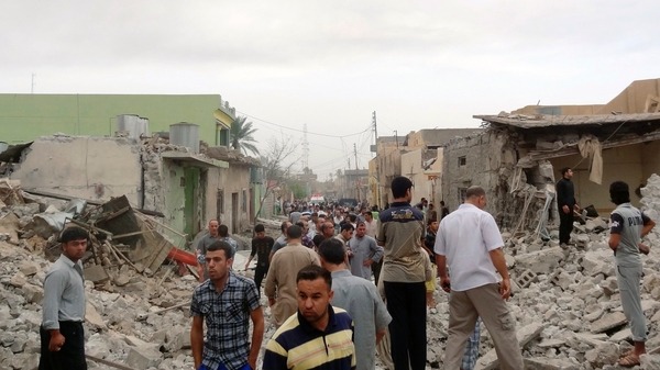 Residents stand amid rubble at blast scene in Tuz Khormatu town in northern Iraq Reuters