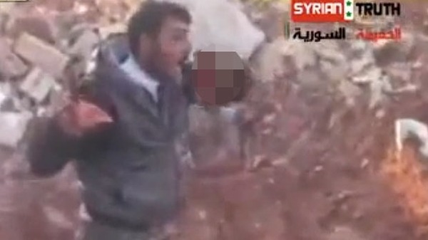 Screen shot of a Syrian rebel cutting out and eating the organs of a regime soldier. Al Arabyia