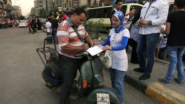 an Egyptian on his motorbike signs a petition for Tamarod Arabic for rebel a campaign against Mursi