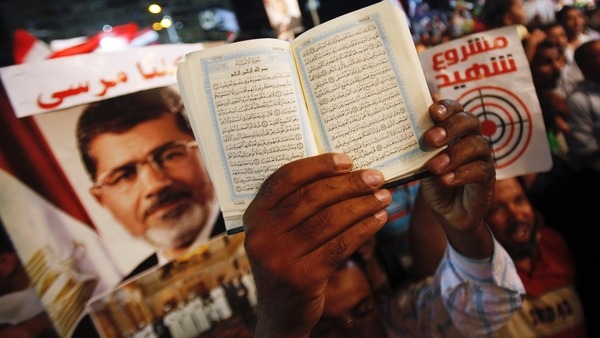 A copy of the Quran is held up near a poster of deposed Egyptian President Reuters