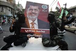 Hamas terrorists hold a poster of Morsi Gaza - Reuters