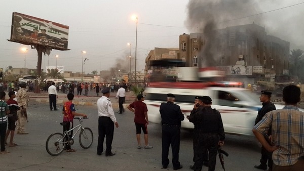 Iraqi policemen and people gather at the site of a car bomb AFP